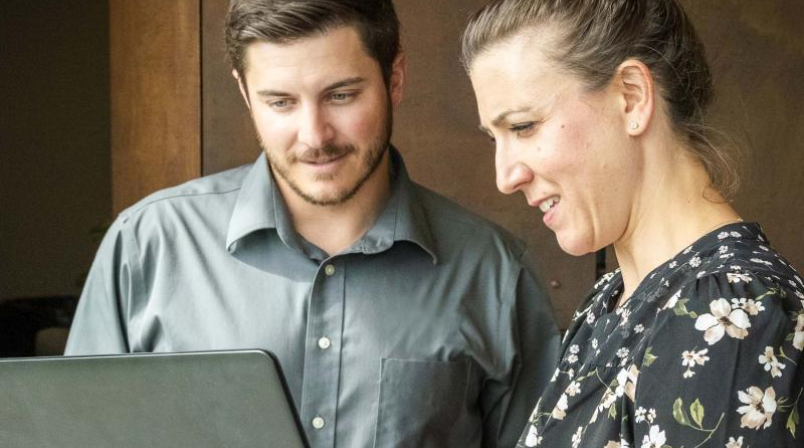 Two people talking in front of a laptop